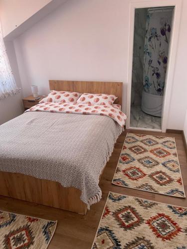 a bedroom with a bed and two rugs at Casa Bunicilor in Nucşoara
