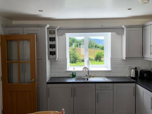 a kitchen with a sink and a window at Mourne Country Cottage in Warrenpoint