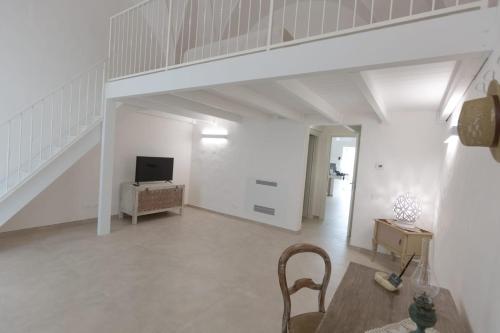 a white living room with a staircase and a chair at CENTO FOGLIE la dimora del borgo in Felline
