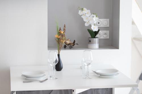 a white table with plates and glasses and flowers at Le Partage des eaux - 4 couchages - Hypercentre - Clim - Wifi in LʼIsle-sur-la-Sorgue