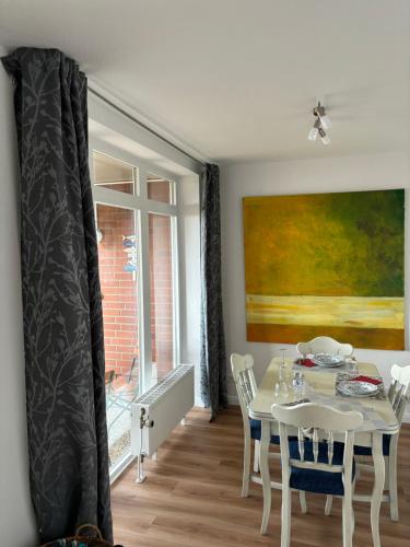 a dining room with a white table and a painting at Ferienwohnung Havenblick in Wilhelmshaven