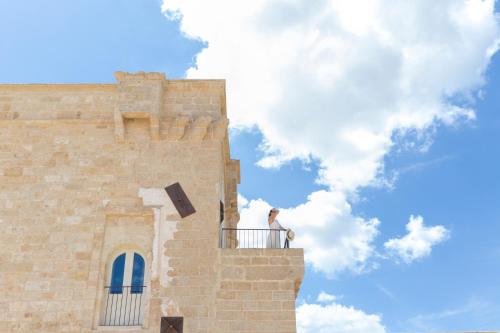 a person standing on a balcony of a building at Masseria Donna Menga - The Leading Hotels of the World in Torre Lapillo