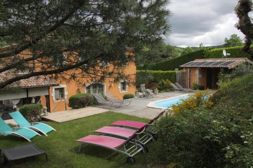 a yard with lounge chairs and a swimming pool at La Bastide de Fontaille in Saint-Félicien