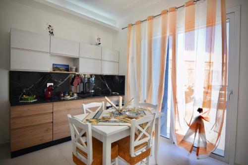 a kitchen with a white table and chairs and a window at Mare Arcobaleno in Marzamemi