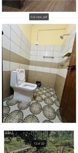 a bathroom with a toilet on a tiled floor at 4 Bedroom Jungle Villa in Panamaram