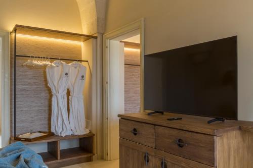 a living room with a tv and a dresser with a flat screen at Masseria Donna Menga - The Leading Hotels of the World in Torre Lapillo