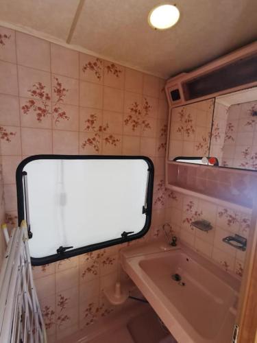 a bathroom with a tub and a sink and a mirror at CampOloHel- przyczepa kempingowa in Hel