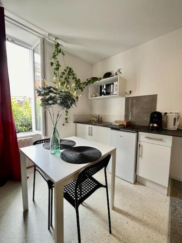 une cuisine avec une table, des chaises et un vase. dans l'établissement Studio 2 Rue Théodore Bac - DABNB, à Limoges