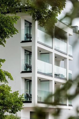 an apartment building with glass balconies and trees at Aqua Bluemica ADULTS ONLY in Międzyzdroje