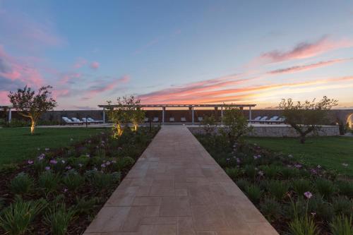 a walkway in a park with a building and flowers at Masseria Donna Menga - The Leading Hotels of the World in Torre Lapillo