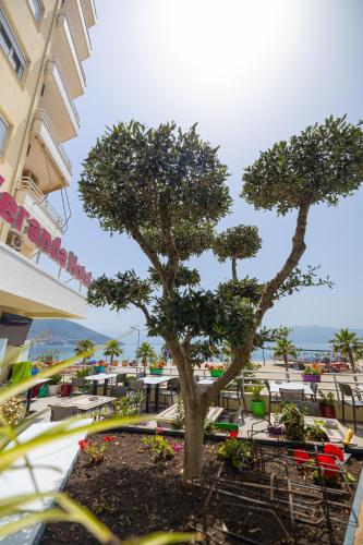 a tree in front of a building with tables and chairs at Veranda Boutique Hotel in Vlorë