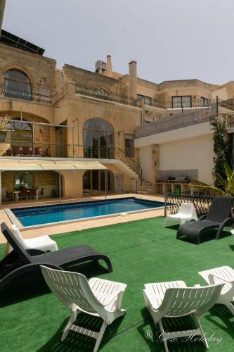 a resort with a pool and chairs and a building at Dar Tat Tork in Xagħra