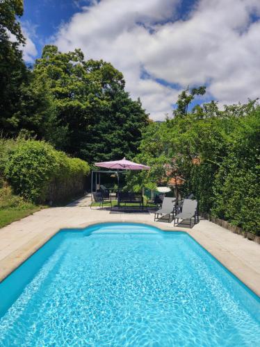 a swimming pool with chairs and an umbrella at Casa das Essências, Quinta de Santo António in Covilhã