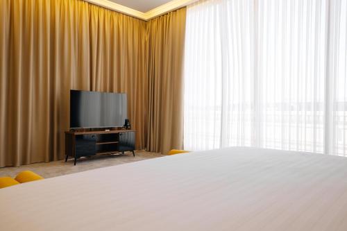 a bedroom with a large bed and a flat screen tv at Kohinur Plaza in Samarkand