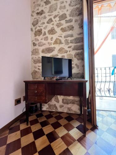 a television on a desk in a room with a stone wall at Il Palazz8 - Dimore di Charme in San Polo dei Cavalieri