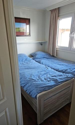 two beds in a bedroom with a window at Chalet nr. 9 Resort Venetië in Giethoorn