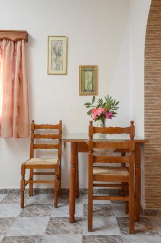 a wooden table with a chair and a vase of flowers at Orama Apartments in Agia Anna Naxos