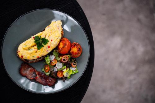 a plate of food with a omelet and potatoes and sausage at Tut Winten a Tranquil Living Villa Ubud in Ubud