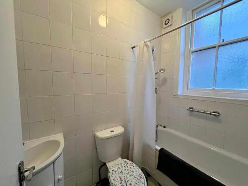 a white bathroom with a toilet and a sink at Delightful One Bed Victorian Flat in Hastings