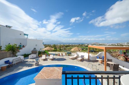 a patio with a swimming pool with chairs and a table at Orama Apartments in Agia Anna Naxos