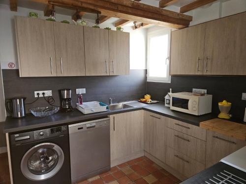 une cuisine avec un lave-linge et un micro-ondes dans l'établissement Maison de la Libération 6 Juin 1944 OMAHA BEACH, à Saint-Laurent-sur-Mer