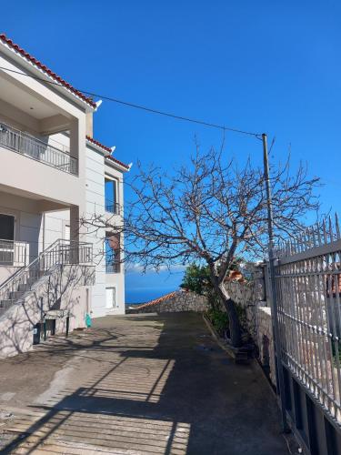 a house with a tree next to a fence at Sofias Studio in Koroni