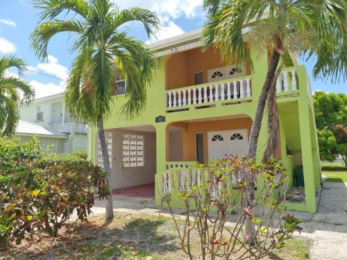 a yellow house with palm trees in front of it at 3 Palms by Coastal View7 in Christ Church