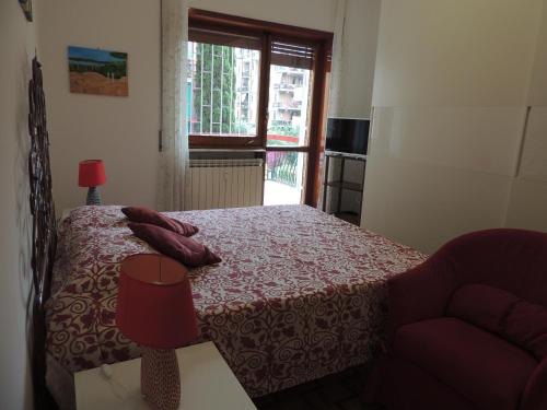 a bedroom with a bed and a chair and a window at La casa di Maro in Lido di Ostia