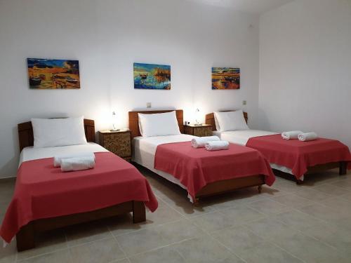 two beds in a room with red sheets and pillows at TheYellow House II Fully Equipped 2BR apartment in Pilaroú
