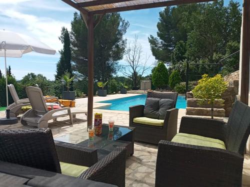 une terrasse avec des chaises, une table et une piscine dans l'établissement Gîte Le Défends, à Flayosc