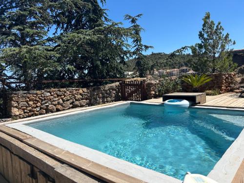une grande piscine avec un mur en pierre dans l'établissement Maison de charme Leucate, à Treilles