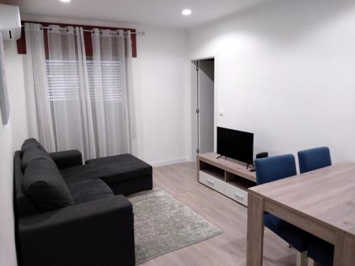 a living room with a couch and a table and a television at Alojamento Almirante in Viseu