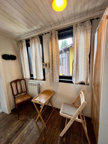 a room with two chairs and a table and two windows at Китанова къща in Koprivshtitsa