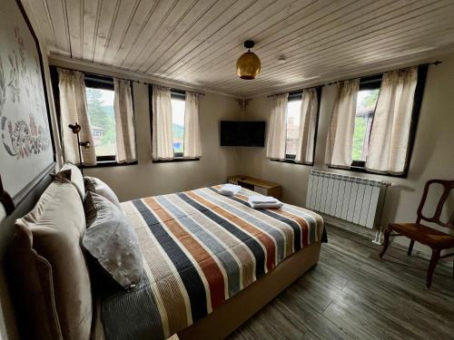 a bedroom with a bed in a room with windows at Китанова къща in Koprivshtitsa