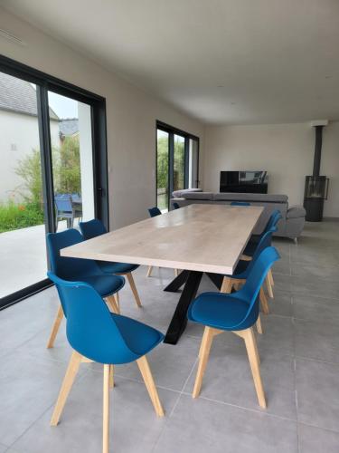 a dining room with a wooden table and blue chairs at Villa l'estran récente vue mer Plounéour-Brignogan-plages in Plounéour-Trez
