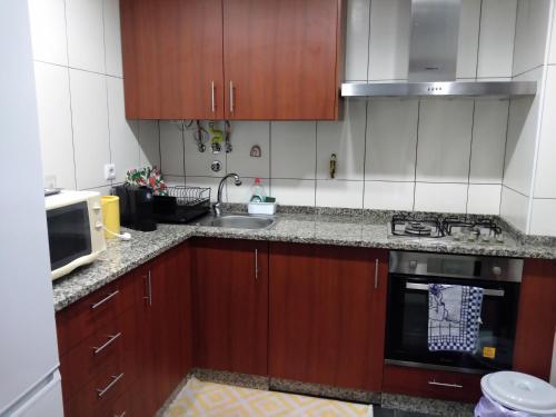 a kitchen with wooden cabinets and a sink and a microwave at Alojamento Almirante in Viseu