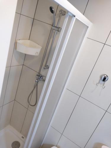 a shower stall in a bathroom with white tiles at Alojamento Almirante in Viseu