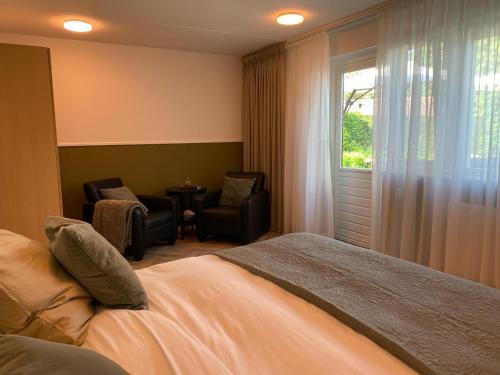 a bedroom with a bed and a chair and a window at La Nuova Casa del Campo (vh De Kamp) in Dinxperlo