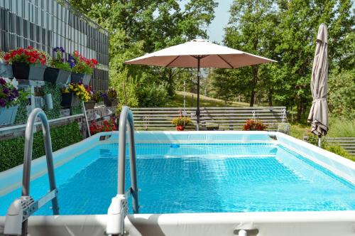 a swimming pool with an umbrella next to a building at Apartman Siesta in Gornji Milanovac