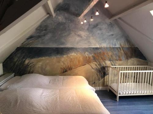 una camera da letto con un dipinto sul muro accanto a una culla di Au coin du loup, monts de Flandres, Zwarteberg a Saint-Jans-Cappel