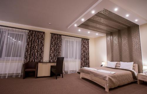 a bedroom with a bed and a desk and curtains at Mіnі Gotel Pozitiv in Horodets'ke