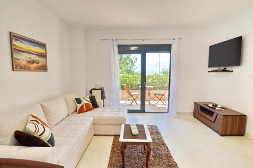 a white living room with a couch and a tv at Radgost Kotor Apartments in Kotor