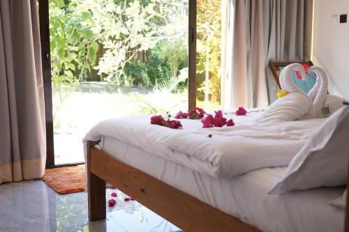 a bed with two swans on it with flowers on it at CosyBe Villas in Praia do Tofo