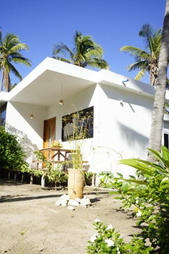 a white house with palm trees in front of it at CosyBe Villas in Praia do Tofo