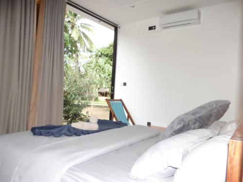 a bedroom with a bed and a large window at CosyBe Villas in Praia do Tofo