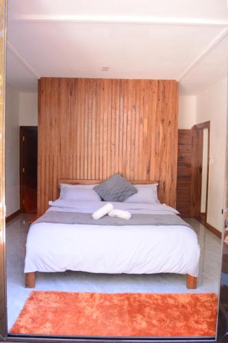 a bedroom with a white bed with a wooden wall at CosyBe Villas in Praia do Tofo