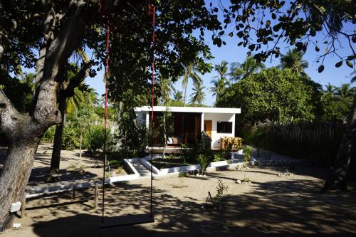 a swing hanging from a tree in front of a house at CosyBe Villas in Praia do Tofo