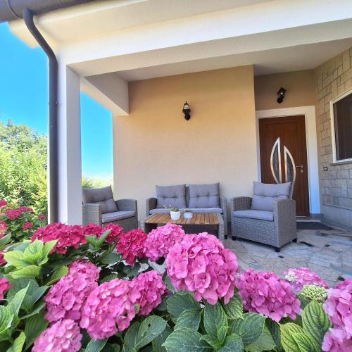 a patio with purple flowers and chairs and a table at Apartment Mita in Grožnjan