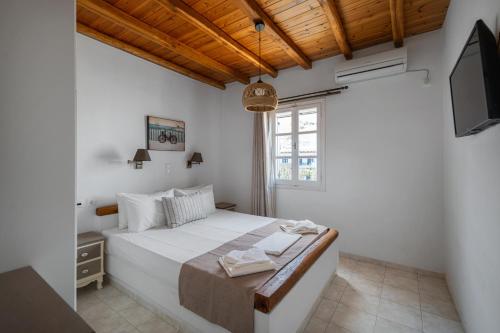 a bedroom with a large white bed with a tv at Galazio Seaside Apartments in Livadakia