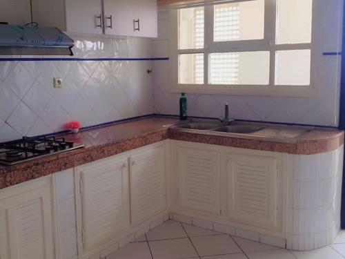a kitchen with white cabinets and a sink and a window at Beach apartment down town in Agadir